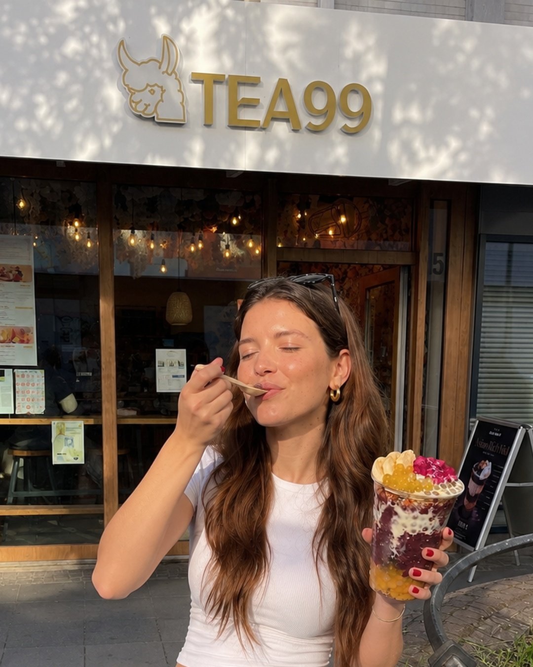 kundin genießt açaí bowl mit goldenem löffel vor tea99 storefront darmstadt — der purple moment